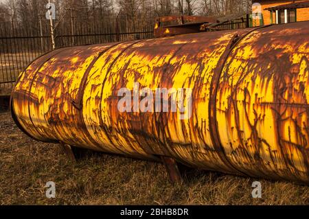 Grand réservoir jaune rouillé sur fond naturel et maison en briques rouges derrière. Banque D'Images