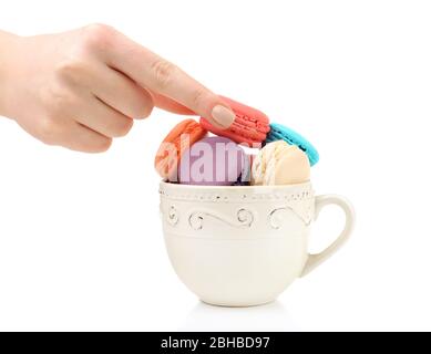 Main féminine prenant de savoureux macarons colorés de tasse isolée sur blanc Banque D'Images