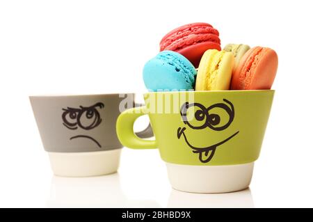 Délicieux macarons colorés dans une tasse isolée sur blanc Banque D'Images