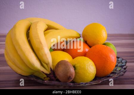 Oranges et citrons sur un bol en verre entre autres fruits Banque D'Images