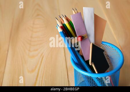 Crayons et notes en papier dans un support en métal et un fond de bureau en bois Banque D'Images
