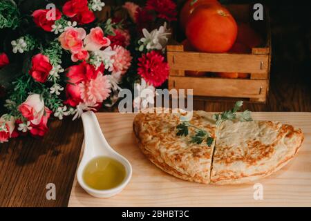 Une dose de deux omelettes sur un bureau de cuisson en bois avec de l'huile, des tomates et un bouquet de fleurs sur les côtés Banque D'Images