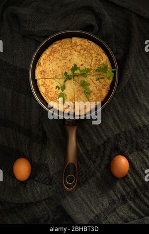Une vue verticale de fermeture à angle élevé d'une omelette divisée en quatre morceaux dans un plat à rôtir et deux œufs sur les côtés Banque D'Images