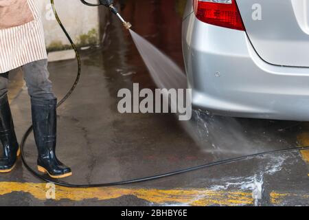 les travailleurs qui lavent une voiture avec de l'eau à haute pression Banque D'Images