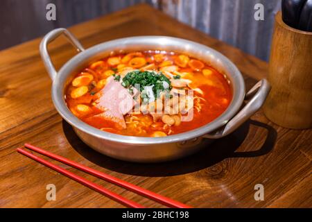 Soupe traditionnelle coréenne de ramen avec kimchi, jambon, saucisse et fromage dans un bol en argent sur table en bois. Cuisine coréenne. Cuisine asiatique savoureuse. Banque D'Images