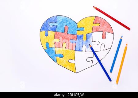 Journée mondiale de sensibilisation à l'autisme. Crayons de couleur et coeur de dessin inachevé à partir de puzzles multicolores. Concept de soins de santé mentale. Banque D'Images