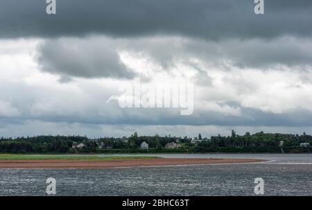 Côte anglo-russe. Maisons résidentielles sur la rive du port de North Rustico. Ciel couvert avec nuages de tempête. Port de North Rustico, Î.-P.-É., Canada Banque D'Images