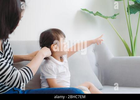 La mère fait des tresses sur la tête de la petite fille. Banque D'Images