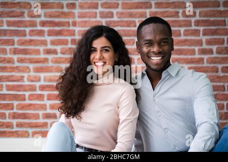Portrait de jeunes couples multiethniques assis sur le sol dans leur nouvelle maison Banque D'Images