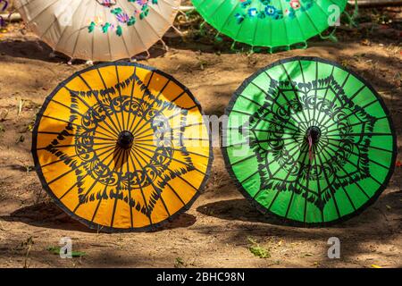 Parapluies asiatiques traditionnels de couleur sur le sol. En vente pour les touristes dans un stand de rue au Myanmar. Banque D'Images