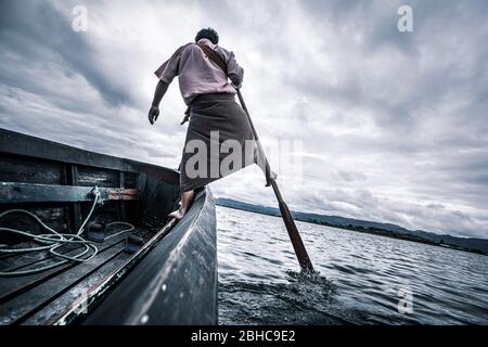 Les pêcheurs locaux pratiquant un style d'aviron distinctif qui implique de se tenir à la poupe sur une jambe et d'envelopper l'autre jambe autour de l'oar. Banque D'Images