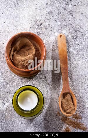 Bol en bois avec argile cosmétique naturelle pour masques de beauté du visage et verre peut hydrater la crème légère pour le visage sur un fond en pierre grise, spa de copie Banque D'Images