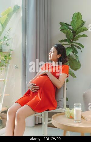 Belle jeune femme asiatique est heureuse de prendre soin de nouveau-né à l'avenir. Concept moderne de maman saine. Banque D'Images