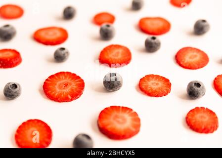 fraises et bleuets mûrs, frais et naturels coupés en rouge, un printemps sain et des fruits d'été, sur fond jaune Banque D'Images