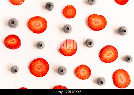 fraises et bleuets mûrs, frais et naturels coupés en rouge, un printemps sain et des fruits d'été, sur fond jaune Banque D'Images