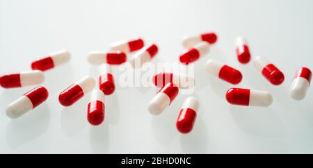 De nombreuses capsules rouges et blanches se propagent sur fond blanc avec ombre. Concept global de santé. Résistance aux antibiotiques. Capsule antimicrobienne Banque D'Images