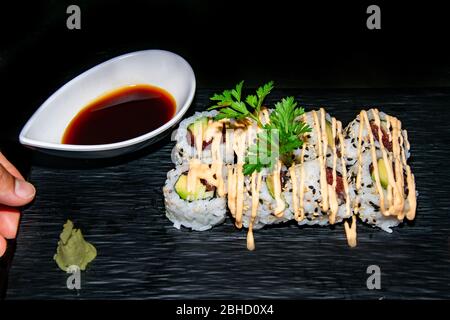 ajoutez la touche finale à une portion de petits pains à sushis californiens épicés au thon recouvert d'une sauce mayonnaise épicée Banque D'Images