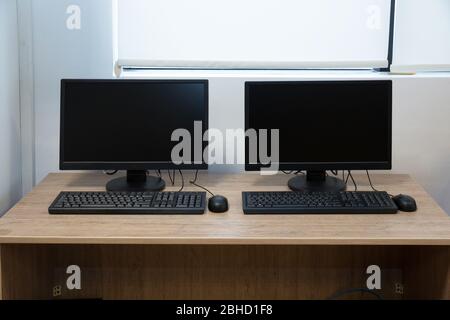deux ordinateurs et un bureau. Clavier et souris . Deux moniteurs d'ordinateur avec un écran noir sur un bureau . Banque D'Images