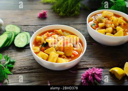 Ragoût de légumes dans un bol blanc. Nourriture sur fond de bois. Repas chaud sain avec pommes de terre, carottes et persil. Banque D'Images