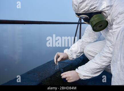 Chercheur recueillant des échantillons pour analyse dans la zone contaminée, instantané de vue latérale rapprochée, concept de pollution de l'environnement Banque D'Images