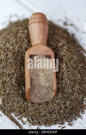 Graines de cumin mises à la terre dans une cuillère en bois sur les graines Banque D'Images