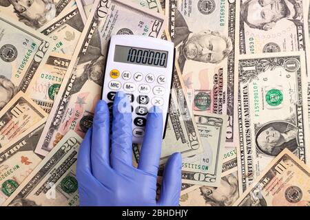 Main dans le gant dettes sur la calculatrice contre le fond de dollars Banque D'Images