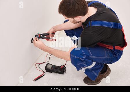 Fil de borne de connexion homme-mains, tenir la pince à sertir. Contexte de conception. Matériaux professionnels. Travaux électriques. Passe-temps masculin Banque D'Images