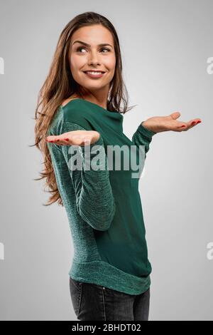 Belle femme debout sur un fond gris avec des bras ouverts et souriants Banque D'Images