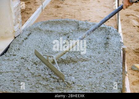 Les ouvriers de la construction nivelant le trottoir de la chaussée en béton dans une nouvelle maison résidentielle Banque D'Images