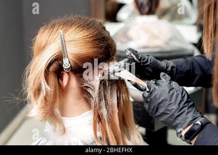 Coiffeur mains est teinture cheveux de femme dans salon de coiffure. Banque D'Images