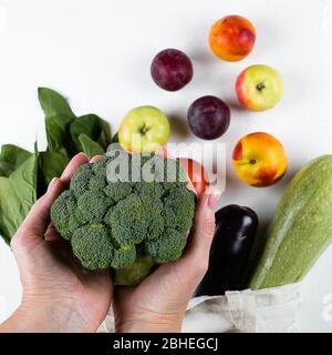 Mains féminines tenant le brocoli. Zéro déchet, soins, concept de santé. Vue de dessus, espace de copie, plat. Banque D'Images