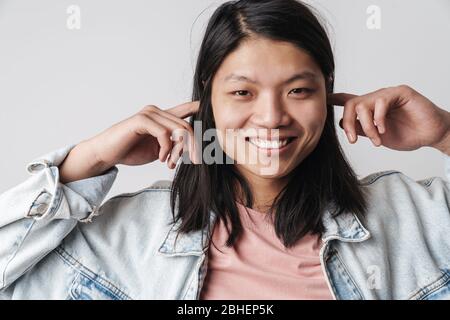 Image de l'homme asiatique content souriant et bouchant ses oreilles isolées sur fond blanc Banque D'Images