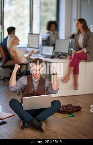 jeune homme d'affaires avec des poings en position "oui", recevant une bonne nouvelle sur son ordinateur portable. concept de jeunes gens d'affaires Banque D'Images