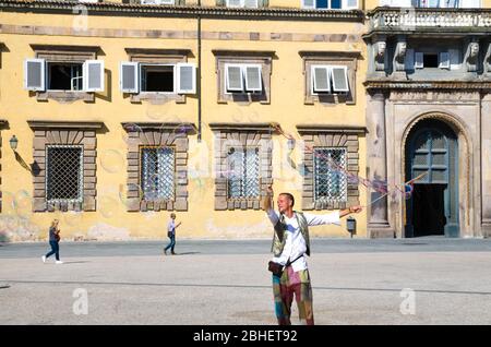 Lucca, Italie, 14 septembre 2018: L'homme souffle des bulles de savon colorées et joue avec de petits enfants sur la place Napoléone près du palais du Palazzo Ducale dans le centre historique de la ville médiévale Lucca Banque D'Images