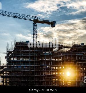 Construction chantier de construction cour au coucher du soleil avec rayons du soleil et nuages Banque D'Images