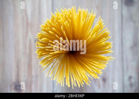 Rade, spaghetti non cuits, farci ensemble. Pâtes italiennes ou macaroni. Œil d'oiseau, vue de dessus, fond de table en bois. Pâtes alimentaires sèches. Banque D'Images