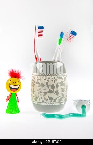Le dentifrice vert et les brosses à dents multicolores se trouvent dans un verre spécial à côté d'un tube de dentifrice. Toujours la vie. Banque D'Images
