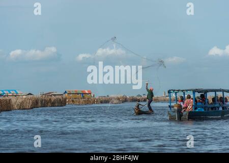 Pêcheur du village de Ganvie jetant net, un village unique construit sur pilotis, sur le lac Nokoue près de Cotonou, Bénin. Banque D'Images