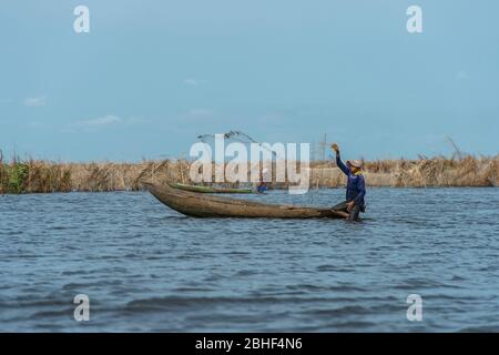 Pêcheur du village de Ganvie jetant net, un village unique construit sur pilotis, sur le lac Nokoue près de Cotonou, Bénin. Banque D'Images