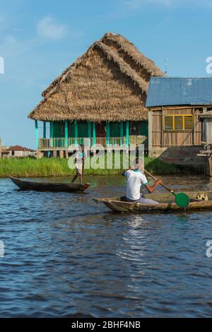 Ganvie village scène avec des bateaux pagayant, est un village unique construit sur pilotis, sur le lac Nokoue près de Cotonou, Bénin. Banque D'Images