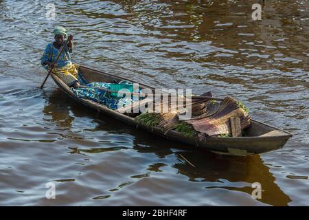 Ganvie village scène avec femme paddling bateau, est un village unique construit sur pilotis, sur le lac Nokoue près de Cotonou, Bénin. Banque D'Images