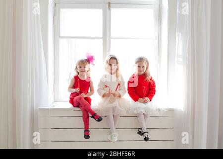 Trois magnifiques petites filles en robes rouges et blancs à la fête Banque D'Images