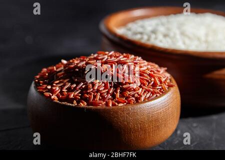 Riz rouge et blanc dans une bols en bois sur table en pierre noire. Céréales sèches non cuites Banque D'Images