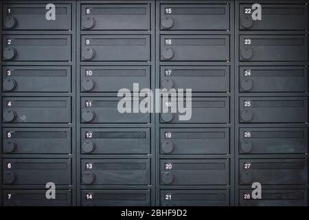 Une rangée de boîtes de dépôt ou de boîtes de courrier en métal dans un appartement de couleur gris foncé Banque D'Images