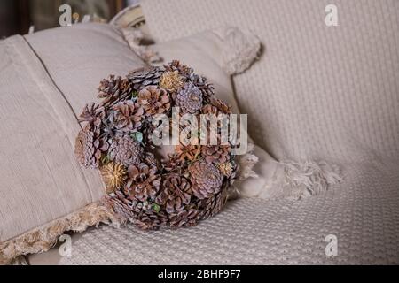 Couronne de Noël dorée de différents cônes naturels sur fond beige. Couronne rurale créative avec des cônes de pin de sapin, des herbes . Carte de vœux Seasons. Copier Banque D'Images