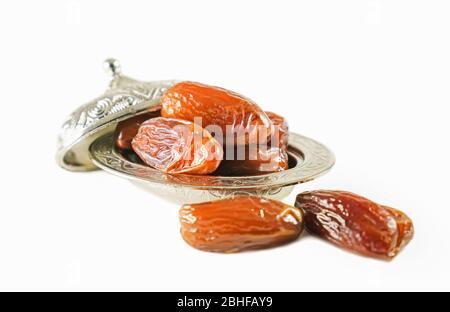 Dates de fruits frais dans un bol en métal argenté sur fond blanc isolé Banque D'Images