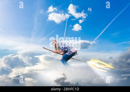 une jeune femme à la décoration moderne vole dans les nuages sur une brosse sorcière avec un sentier de feu Banque D'Images