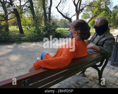 Couple ancien / grands-parents ( homme / homme & femme / femme ) portant un masque facial ( masque chirurgical ), assis sur un banc de parc - covid-19 corona virus verrouillage Banque D'Images