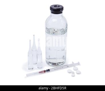 ampoules médicales en verre avec médicaments, flacon avec solution saline, seringue et pilules isolées sur fond blanc Banque D'Images