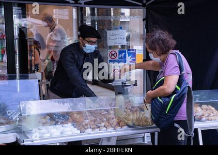 Une femme et un préposé aux magasins portant des masques de visage pendant le Ramadan au milieu de la pandémie du virus corona. À Saint Denis, une banlieue parisienne où la population est majoritairement musulmane, les gens se rencontrent sur les marchés et les bouchers pour préparer des repas du Ramadan en temps de pandémie. Ils portent des masques pour se protéger du virus, mais les distanciation sociale sont loin d'être remplies. Banque D'Images